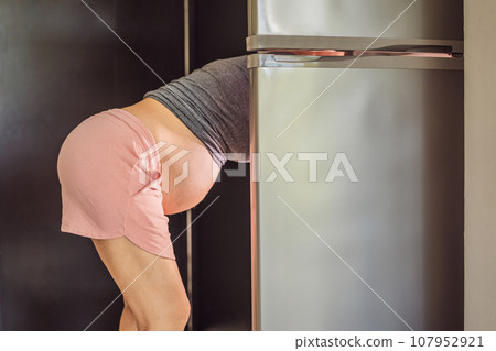 Young Pregnant Woman Looking For Food In Refrigerator 107952921