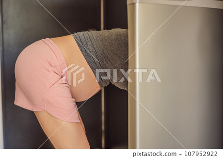 Young Pregnant Woman Looking For Food In Refrigerator 107952922