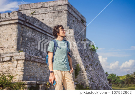Male tourist enjoying the view Pre-Columbian Mayan walled city of Tulum, Quintana Roo, Mexico, North America, Tulum, Mexico. El Castillo - castle the Mayan city of Tulum main temple 107952962