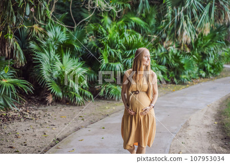 happy pregnant woman walking in the park 107953034