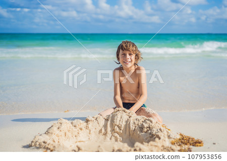 Young boy's pure delight as he explores the sandy playground of the beach, shaping dreams with grains of sand Young boy's pure delight as he explores the sandy playground of the beach, shaping dreams with grains of sand 107953856