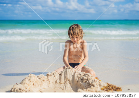 Young boy's pure delight as he explores the sandy playground of the beach, shaping dreams with grains of sand Young boy's pure delight as he explores the sandy playground of the beach, shaping dreams with grains of sand 107953857