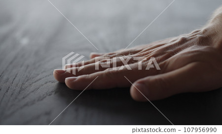 man hand touches black oak table surface 107956990