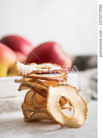 Organic healthy dried apple rings with red ripe apples on light bavkground. 107957998