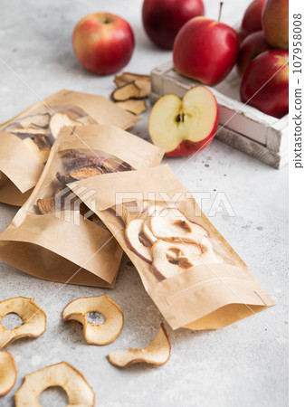 Packages of assorted sweet dried apple chips and slices on light background. Packages of assorted sweet dried apple chips and slices on light background. 107958008