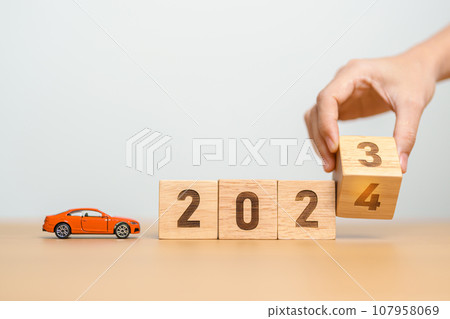 2023 flipping to 2024 year block with car model on table. Automobile Tax, Car Insurance, Financial, vehicle Repair and Maintenance and New Year concept 107958069