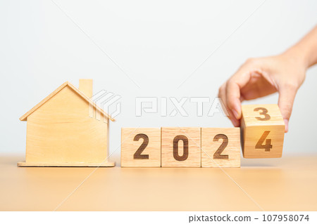 hand flip 2023 to 2024 block with house model. real estate, Home loan, tax, investment, financial, savings and New Year Resolution concepts 107958074