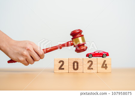 Car Law, Insurance, auto Tax, Auction and Bidding concepts. 2024 year block with crashed small toy car models with Judges gavel on desk in courthouse. 107958075