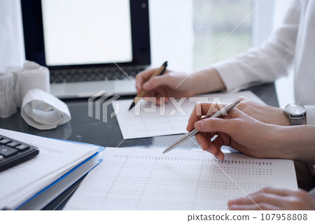 Two accountants use a laptop computer for counting taxes or revenue balance. Business, audit, and taxes concepts 107958808
