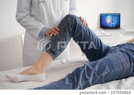 Doctor and patient are at the usual medical inspection in the clinic. Therapist examines a young woman's knee. Medicine concept 107958868