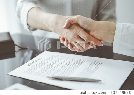 Business people signing contract papers while sitting at the glass table in office, closeup. Partners or lawyers working together at meeting. Teamwork, partnership, success concept Business people signing contract papers while sitting at the glass table in office, closeup. Partners or lawyers working together at meeting. Teamwork, partnership, success concept 107959638