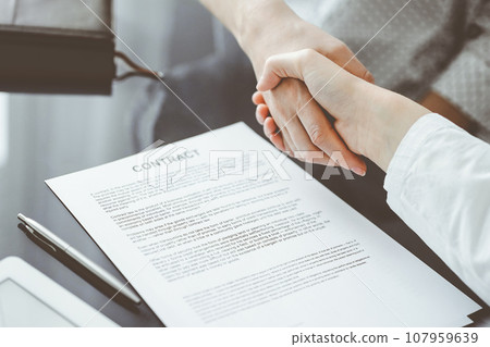 Business people signing contract papers while sitting at the glass table in office, closeup. Partners or lawyers working together at meeting. Teamwork, partnership, success concept Business people signing contract papers while sitting at the glass table in office, closeup. Partners or lawyers working together at meeting. Teamwork, partnership, success concept 107959639