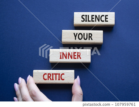 Silence your inner critic symbol. Wooden blocks with words Silence your inner critic. Beautiful deep blue background. Businessman hand. Business and Silence your inner critic concept. Copy space. Silence your inner critic symbol. Wooden blocks with words Silence your inner critic. Beautiful deep blue background. Businessman hand. Business and Silence your inner critic concept. Copy space. 107959761