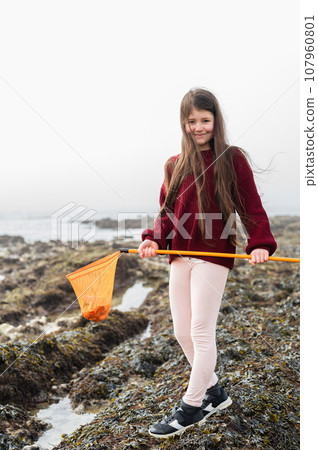Girl with dark long hair rock pooling at Hope Gap Beach between Seaford and Eastbourne, East Sussex. Beach and sea in foggy morning 107960801
