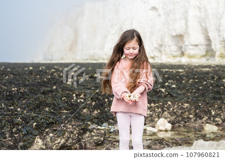 Little girl between Seaford and Eastbourne, East Sussex. Beach and sea in foggy morning 107960821