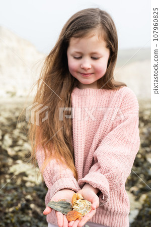 Little girl rock pooling and collecting sea shells at Hope Gap Beach between Seaford and Eastbourne, East Sussex. Beach and sea in foggy morning Little girl rock pooling and collecting sea shells at Hope Gap Beach between Seaford and Eastbourne, East Sussex. Beach and sea in foggy morning 107960825
