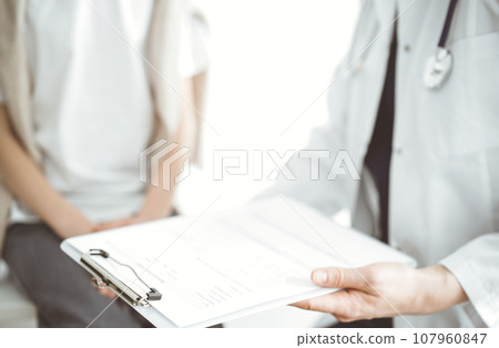 Doctor and child patient. The physician is holding clipboard with medication history records form near a boy. The concept of ideal health in medicine 107960847
