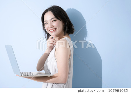 A woman using a computer, the background is a refreshing blue A woman using a computer, the background is a refreshing blue 107961085