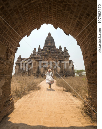 Young Tourist Woman Running in White Dress to Old Traditional Burmese Temple. Travel Adventure 107962470