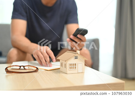 A detached house on table with man using calculator for planning and calculating money for buy house or estates 107963030
