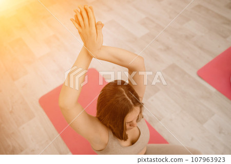 Girl does yoga. Young woman practices asanas on a beige one-ton background. 107963923