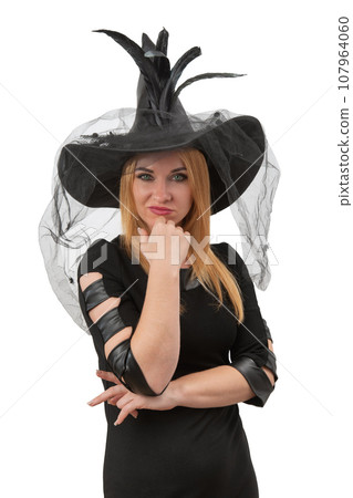 Attractive young woman with green eyes looks straight in camera, in black witch hat. Halloween party, white background. Young witch, vertical frame Attractive young woman with green eyes looks straight in camera, in black witch hat. Halloween party, white background. Young witch, vertical frame 107964060