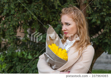 Frustrated disgruntled red-haired woman with bouquet of flowers arms crossed. Sad girl waits outside. Vertical frame. Frustrated disgruntled red-haired woman with bouquet of flowers arms crossed. Sad girl waits outside. Vertical frame. 107964065