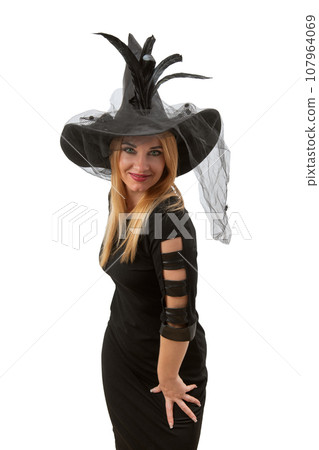 Attractive sexy woman in black witch hat and dress looking in camera. Halloween party, white background. Young witch, vertical frame Attractive sexy woman in black witch hat and dress looking in camera. Halloween party, white background. Young witch, vertical frame 107964069