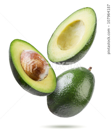 Ripe avocado and two halves flyon a white background. Isolated Ripe avocado and two halves flyon a white background. Isolated 107964187