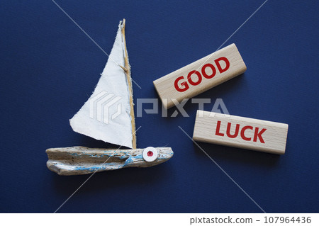 Good luck symbol. Wooden blocks with words Good luck. Beautiful deep blue background with boat. Business and Good luck concept. Copy space. Good luck symbol. Wooden blocks with words Good luck. Beautiful deep blue background with boat. Business and Good luck concept. Copy space. 107964436