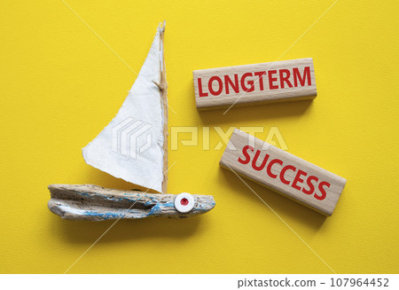 Longterm success symbol. Wooden blocks with words Longterm success. Beautiful yellow background with boat. Business and Longterm success concept. Copy space. 107964452