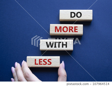 Do more with less symbol. Concept words Do more with less on wooden blocks. Beautiful deep blue background. Businessman hand. Business and Do more with less concept. Copy space. 107964514