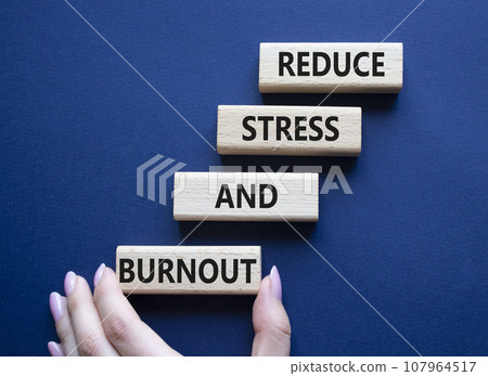 Reduce Stress and Burnout symbol. Concept word Reduce Stress and Burnout on wooden blocks. Beautiful deep blue background. Businessman hand. Business and Reduce Stress and Burnout concept. Copy space Reduce Stress and Burnout symbol. Concept word Reduce Stress and Burnout on wooden blocks. Beautiful deep blue background. Businessman hand. Business and Reduce Stress and Burnout concept. Copy space 107964517
