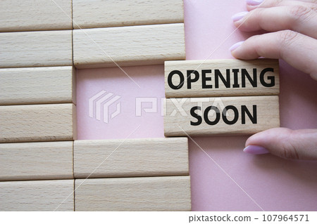 Opening soon symbol. Concept word Opening soon on wooden blocks. Businessman hand. Beautiful pink background. Business and Opening soon concept. Copy space 107964571