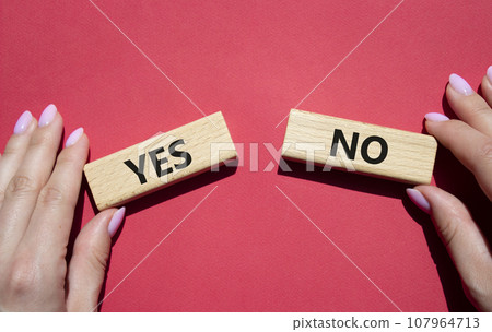 Yes or No symbol. Concept word Yes or No on wooden blocks. Businessman hand. Beautiful red background. Business and Yes or No concept. Copy space Yes or No symbol. Concept word Yes or No on wooden blocks. Businessman hand. Beautiful red background. Business and Yes or No concept. Copy space 107964713