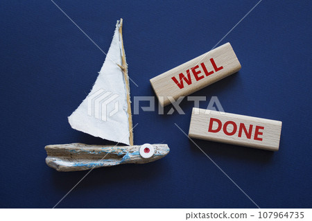Well done symbol. Wooden blocks with words Well done. Beautiful deep blue background with boat. Business and Well done concept. Copy space. 107964735