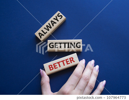 Always getting better symbol. Wooden blocks with words Always getting better. Beautiful deep blue background. Businessman hand. Business and Always getting better concept. Copy space. Always getting better symbol. Wooden blocks with words Always getting better. Beautiful deep blue background. Businessman hand. Business and Always getting better concept. Copy space. 107964773
