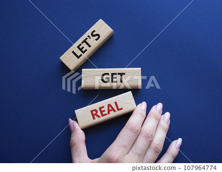 Lets get real symbol. Concept words Lets get real on wooden blocks. Beautiful deep blue background. Businessman hand. Business and Lets get real concept. Copy space. 107964774