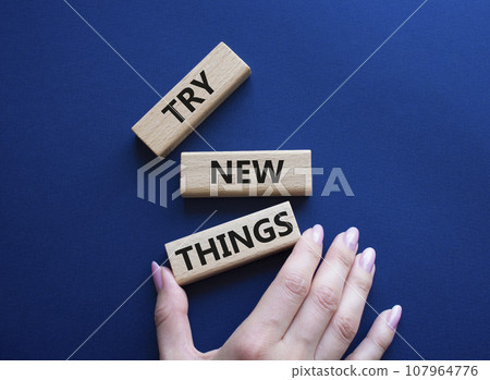 Try new Things symbol. Concept words Try new Things on wooden blocks. Businessman hand. Beautiful deep blue background. Business and Try new Things concept. Copy space. 107964776