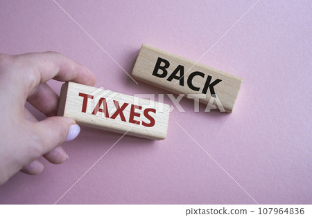 Back Taxes symbol. Concept word Back Taxes on wooden blocks. Businessman hand. Beautiful pink background. Business and Back Taxes concept. Copy space 107964836