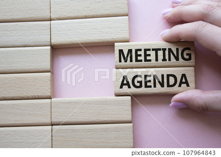 Meeting agenda symbol. Concept word Meeting agenda on wooden blocks. Businessman hand. Beautiful pink background. Business and Meeting agenda concept. Copy space Meeting agenda symbol. Concept word Meeting agenda on wooden blocks. Businessman hand. Beautiful pink background. Business and Meeting agenda concept. Copy space 107964843