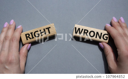 Right or Wrong symbol. Concept word Right or Wrong on wooden blocks. Businessman hand. Beautiful grey background. Business and Right or Wrong concept. Copy space 107964852