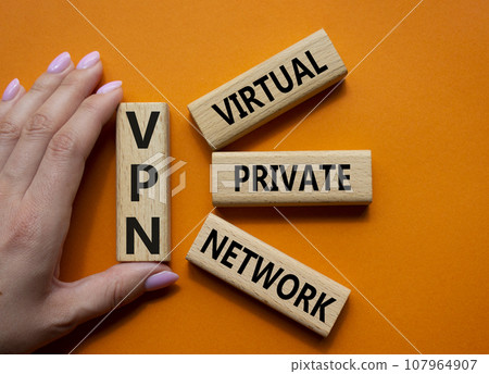 VPN - Virtual Private Network. Wooden cubes with word VPN. Businessman hand. Beautiful orange background. Business and VPN concept. Copy space. VPN - Virtual Private Network. Wooden cubes with word VPN. Businessman hand. Beautiful orange background. Business and VPN concept. Copy space. 107964907