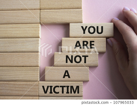 You are not your a victim. Wooden blocks with words You are not a victim. Beautiful pink background. Businessman hand. Business and You are not a victim. Copy space. 107965033