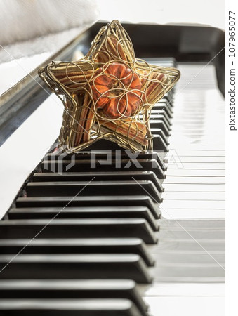 Golden star shaped mesh case is filled with dried fruits stand on the Piano Keyboard. 107965077