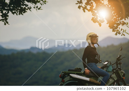 woman wearing safety helmet sitting on small enduro motorcycle against beautiful scenic of khao yai national park thailand 107965102