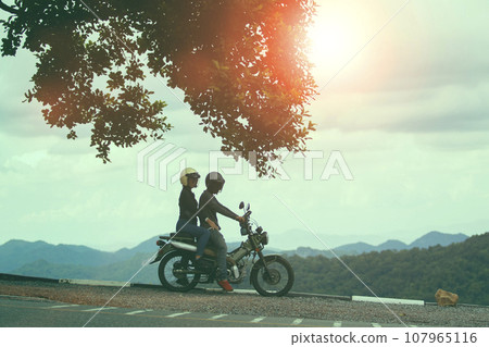 couples wearing safety helmet sitting on small enduro motorcycle against beautiful natural mountain scene at khaoyai national park thailand 107965116