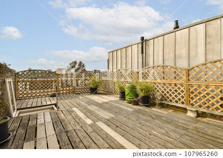 a wooden deck with potted plants on it and a blue sky in the background, taken from an angle a wooden deck with potted plants on it and a blue sky in the background, taken from an angle 107965260