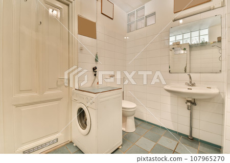 a laundry room with a washer, toilet and sink in the photo is taken from the front door to the bathroom 107965270