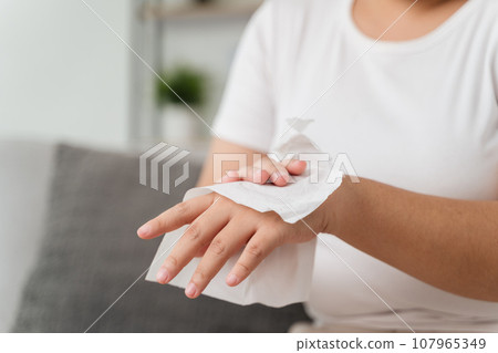 Woman wipes cleaning her hand with a tissue paper towel. Healthcare and medical concept. 107965349